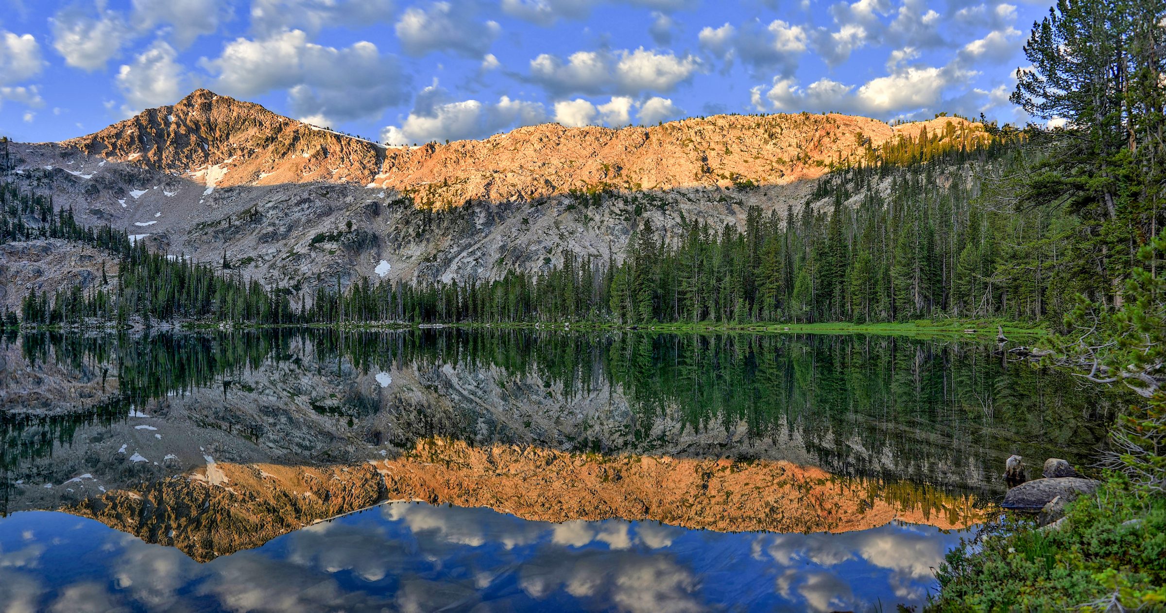 More — First light tops the ridge; the still lake gives it back doubled.